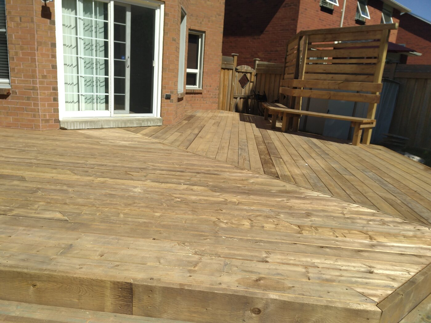 Wide custom backyard deck with bench and privacy screen